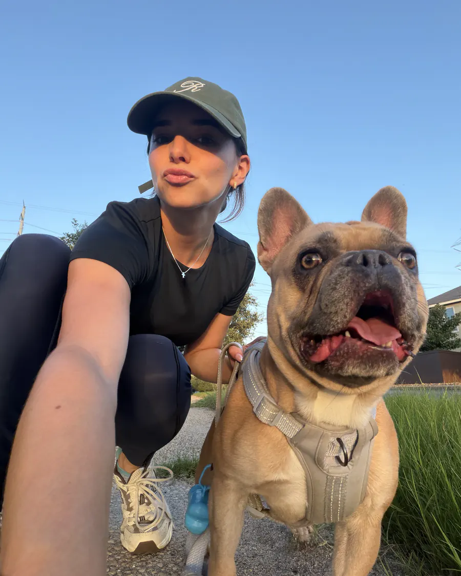 Natalia crouching next to her French bulldog on a sunset walk
