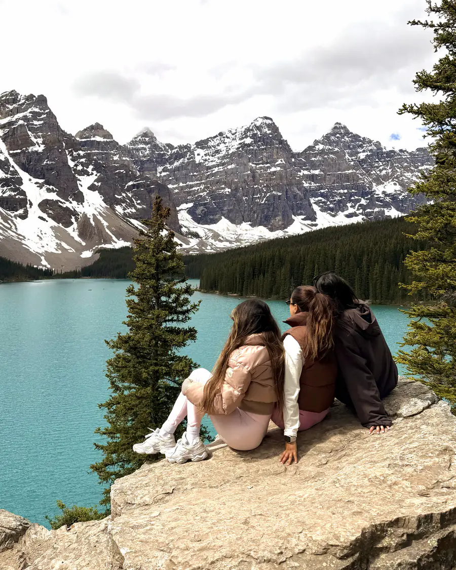 Natalia and two friends sitting on a rock above a turquoise lake in Banff