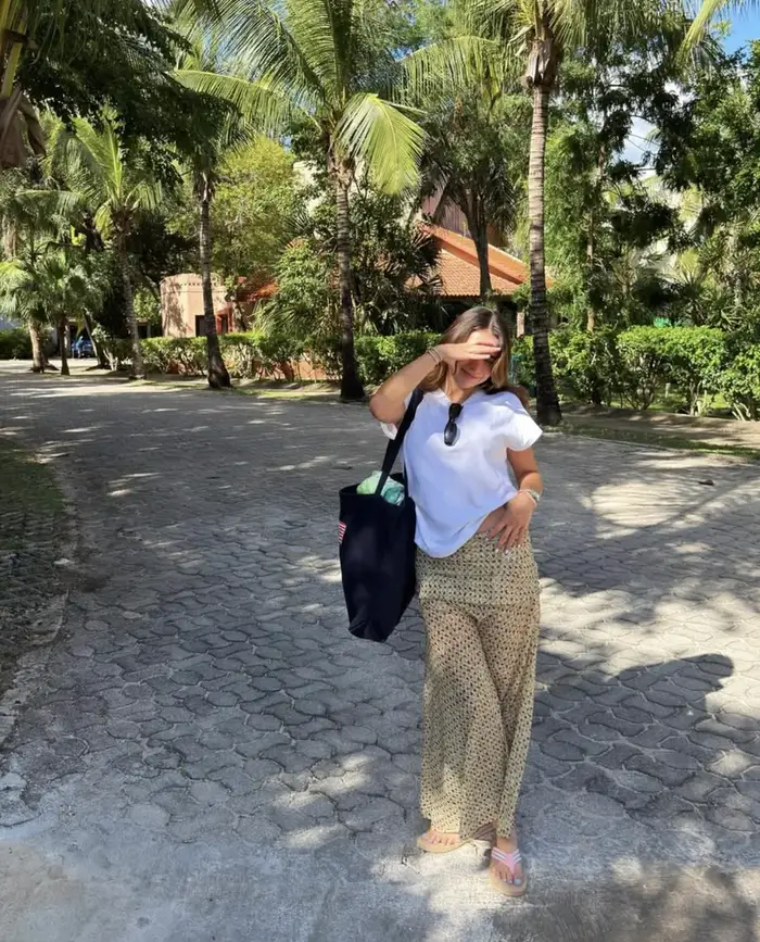 Natalia walking between palm trees at the beach
