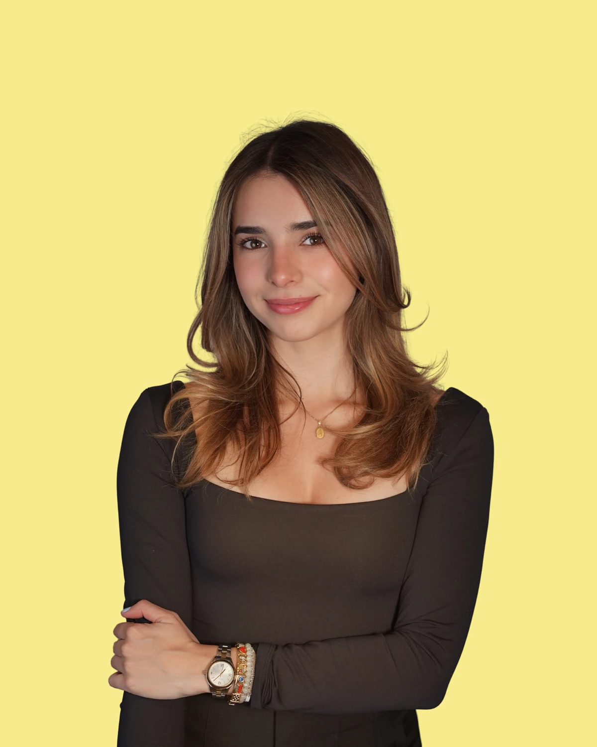 Natalia Bustamante smiling with her arms crossed on a butter-yellow background
