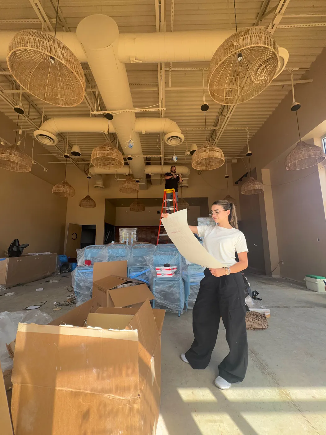 Natalia reviewing blueprints inside a restaurant under construction